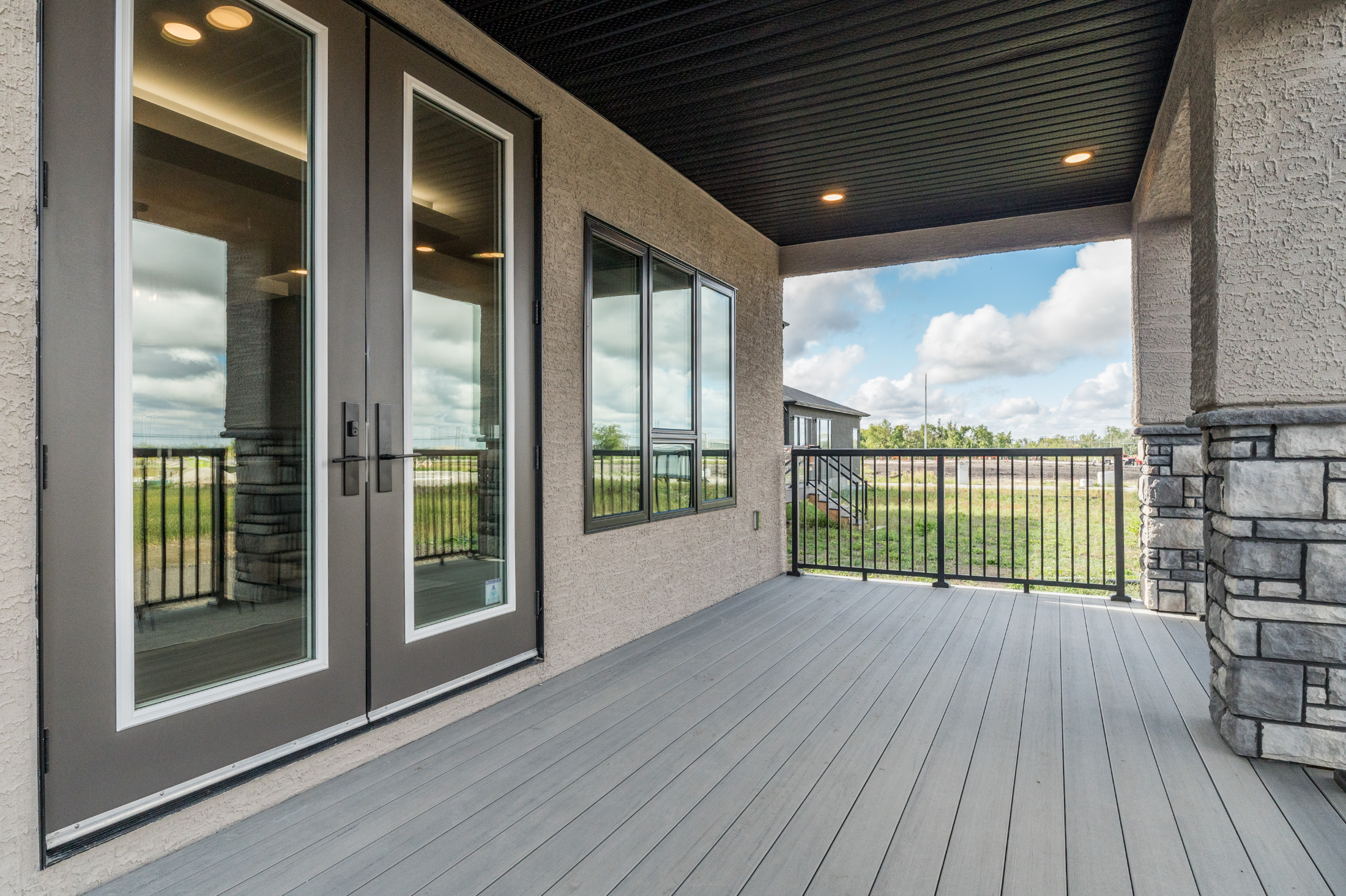         Covered composite decking with stone columns and pot lighting
